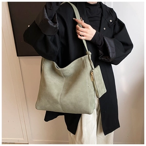 Detail view of light green suede tote bag with matching inner pouch on model outfit