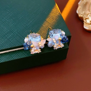 Macro shot of blue butterfly crystal stud earrings with gold beads and white pearls