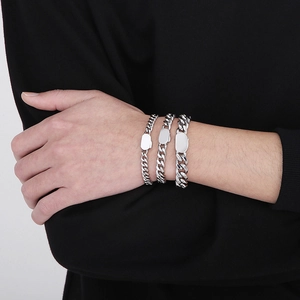 Silver stainless steel Cuban link bracelets for men in three varying widths on a model