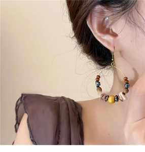Detail of bohemian hoop earrings with beads and shell fragments worn by a model