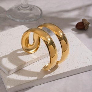 Polished double-layer 18K gold-plated stainless steel open bangle on white stone slabs