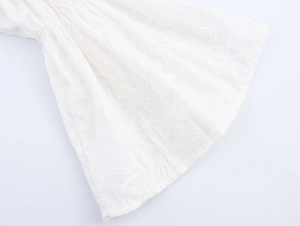 Détail de la broderie en dentelle blanche et texture des manches évasées élégantes