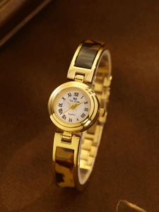 Detail of gold metal and amber tortoiseshell resin link strap on women's quartz watch
