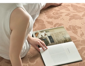 Detail view of a vintage floral brown round rug with a person reading a book on it
