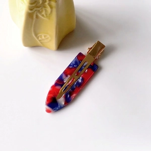 Detailed close-up of marble pattern acetate hair clip with golden metal spring clip