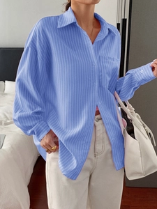Close-up of blue striped long sleeve shirt featuring front buttons and a chest pocket