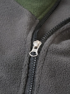 Detail shot of heavy-duty metal zipper on fleece tactical pullover with olive green contrast