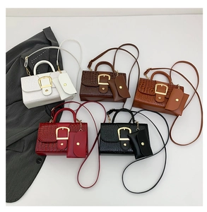 Détail de cinq sacs motif crocodile en blanc, marron, rouge et noir avec mini pochettes
