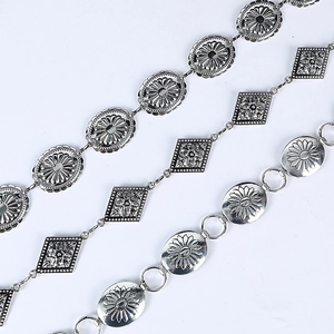 Three bohemian silver metal waist chains with vintage floral patterns on white background
