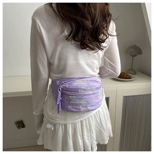 Detail of purple crossbody bag featuring colorful abstract embroidery and woven zipper pull
