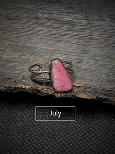 Detail view of July pink raw gemstone set on a vintage dark metal adjustable open ring