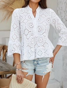 Détail de la blouse blanche à col en V avec broderie ajourée complexe et boutons à l'avant