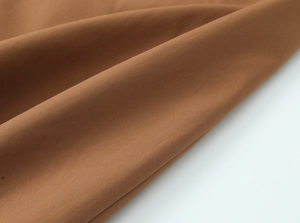 Nahaufnahme des braunen Trenchcoat-Stoffs mit detaillierter Köperbindung und Material