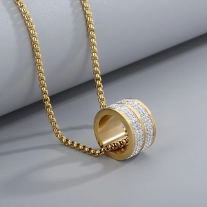 Detail of gold-plated woven chain with a circular pendant set with three rows of white crystals