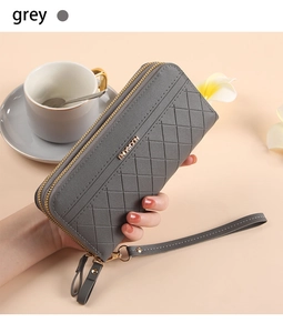 Long grey quilted wallet with double zippers and wrist strap held by a model