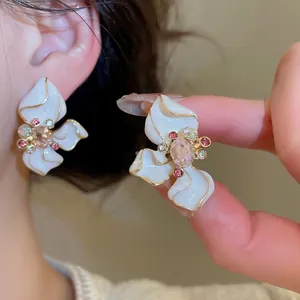 Elegant floral stud earrings with white enamel petals and pink crystals for women