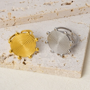 Detailed close-up of gold and silver spiral rings with beaded edges on stone background