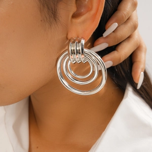 Macro detail of layered silver geometric circular earrings worn by a professional model