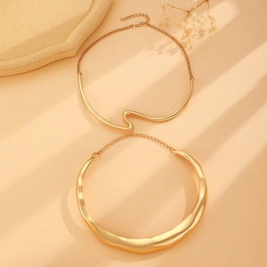 Chic gold wave layered necklace set with geometric crescent choker on a stone tray