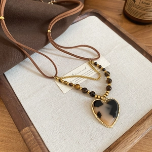 Macro view of heart pendant featuring tiger eye beads and tortoise texture on wood background