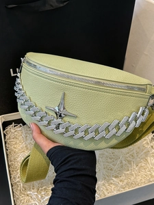 Detail of avocado green litchi leather crossbody bag with sparkling Cuban chain and star