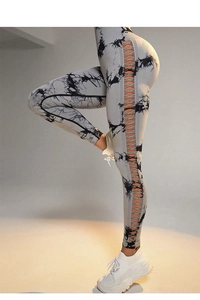 Detail of high waisted tie dye yoga pants featuring side cut-out criss-cross bandages