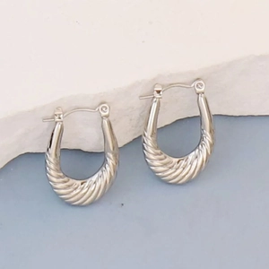 Detail of silver U-shaped hoop earrings with twisted texture and polished metal finish