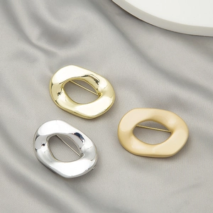 Detailed shot of irregular geometric round brooches in gold, silver, and matte beige finish