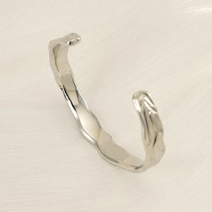 Close-up of irregular wave texture and polished finish on a silver stainless steel bangle