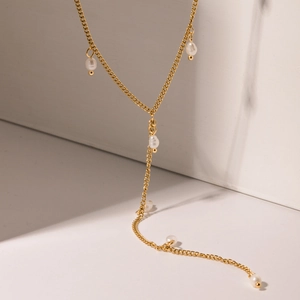 Macro detail of French vintage 18K gold plated Y-shaped necklace with pearl tassels