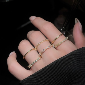 Macro detail of five gold-tone geometric zircon rings stacked on model's hand