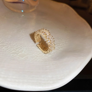 Detail view of gold-plated cross ring with rectangular cubic zirconia on ceramic plate