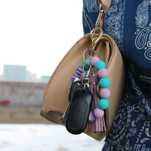 Detail of silicone bead wristlet keychain with purple leather tassel and gold ring