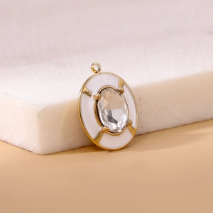 Macro view of gold-plated oval pendant with white enamel and clear cubic zirconia detail