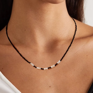Collier en acier inoxydable doré 18k avec cristaux noirs et perles blanches sur un mannequin
