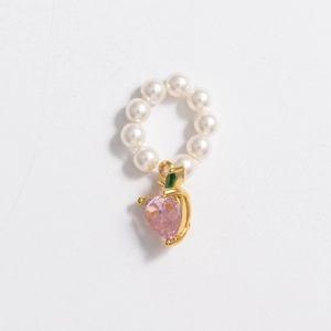 Detail of faux pearl necklace featuring a pink heart gemstone pendant with gold accents