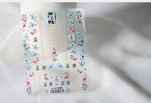 Detail of TS-003 5D nail art decals with floral patterns on soft fabric background