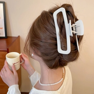 Dettaglio di un fermaglio per capelli rettangolare bianco crema opaco in uno chignon basso