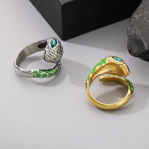 Detailed view of silver and gold snake rings with green enamel scales and gemstone eyes