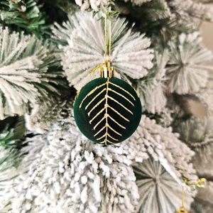 Détail d'une boule de Noël en velours vert foncé avec motifs dorés sur un sapin