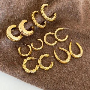 Close-up of assorted geometric gold earrings featuring twisted and crescent shapes