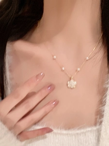 Close-up of gold necklace with pavé diamond flower pendant and small pearls on model
