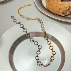 Artistic detail of baroque pearl necklace with mixed silver and gold chains on metal plate