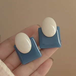 Detail showing vintage geometric earrings with blue squares and white oval accents