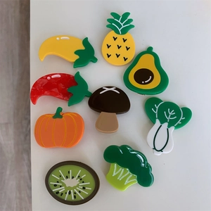 Flat lay of 9 colorful acetate fruit and vegetable hair clips on white background
