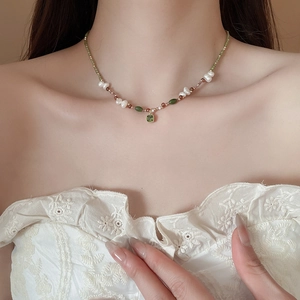 Detail of 18k gold plated necklace with freshwater pearls and green zircon pendant on model