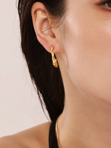 Close-up detail of golden bamboo-textured rectangular hoop earrings on a model's ear