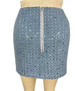 Détail d'une mini-jupe en jean bleu clair avec des paillettes argentées et un zip métallique