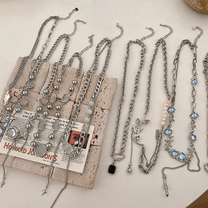Detail of silver necklaces with cat eye stones and pearls on a stone background