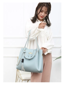 Light blue crossbody bag detail featuring gold buckle and leather tassel with black beads